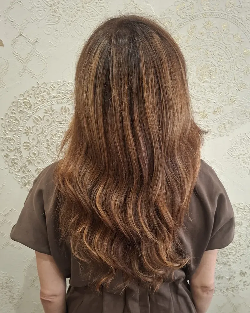 Ondas suaves en cabello castaño realizadas en NÜMIA